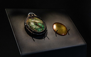 A watch with a patina finish and a smooth copper lid placed against a black velvet background.