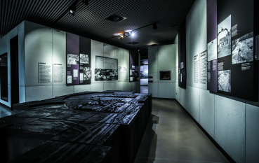 A view of the permanent exhibition, with a black model in the foreground and panels displaying historical information and photographs in the background.