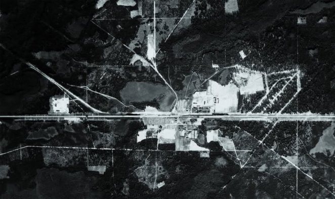 Czarno-białe zdjęcie lotnicze, teren byłego obozu zagłady w Sobiborze oraz las go otaczający, widoczna linia kolejowa 