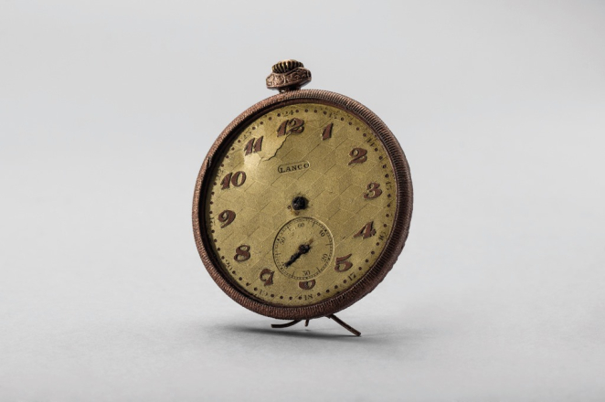 A pocket watch with a brass-coloured dial, lacking its hands and protective glass.