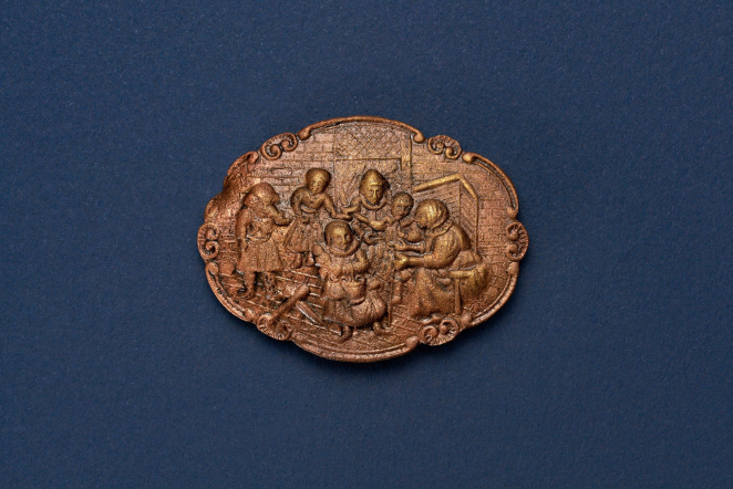 Elliptical metal brooch with six double scrolls in the cover, with a multi-figure scene from the painting The Feast of St. Nicholas in the center.