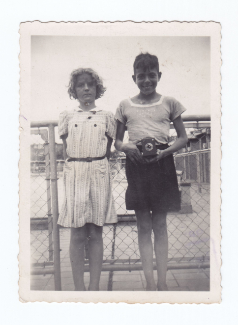 Czarno-białe zdjęcie, nastoletni chłopiec i dziewczynka, chłopiec trzyma w ręku aparat fotograficzny