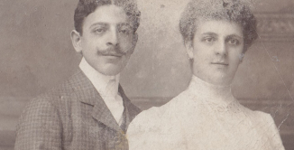 Zdjęcie portretowe mężczyzny i kobiety w średnim wieku, mężczyzna z podkręconym do góry wąsem, kobieta w białej sukni z upiętymi do góry włosami.