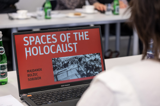 Monitor laptopa, czerwony baner z napisem: Spaces of the Solocaust: Majdanek, Beżec, Sobibór