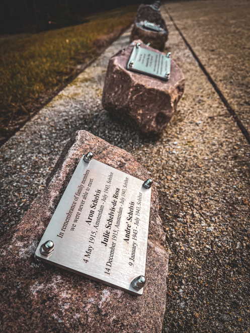 Row of stones with metal plaques placed along the gravel path.