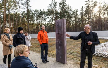Grupa osób oraz przewodnik przy stelli. 