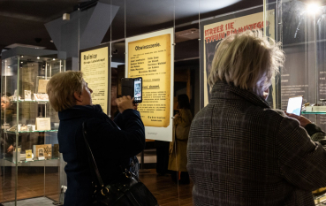 Dwie kobiety robią zdjęcia telefonem komórkowym na wystawie.